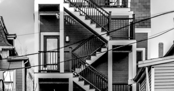 Black and white photo of a multi-family, tri-level home with staircase