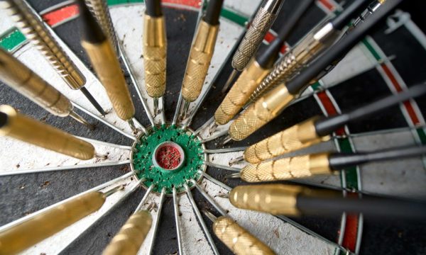 Dartboard with many darts missing the bullseye - Power Marketing